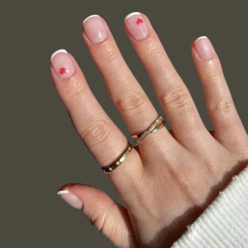 girls hand having Tiny Hearts on Red Tips of nails